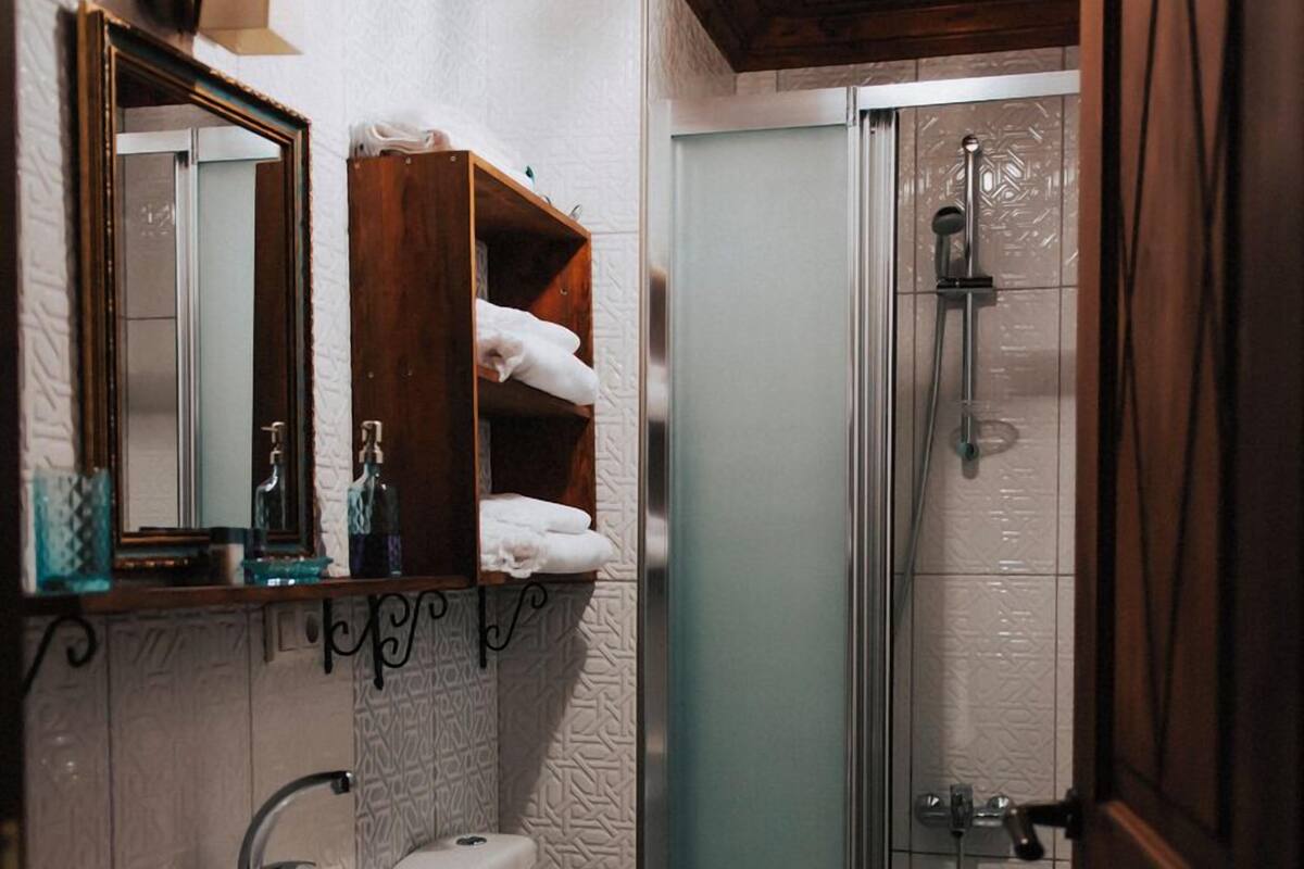 Un baño con techo de madera, un lavamanos, un inodoro y una ducha.