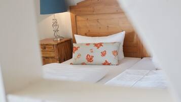 Un dormitorio con cabecera de madera, mesita de noche con lámpara y almohada estampada.