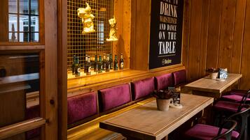 Un interno ristorante con pareti in legno, una zona bar con bottiglie e un cartello che invita a ballare sul tavolo.