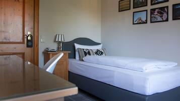 Una habitación de hotel con cama, escritorio, silla, lámpara y puerta.