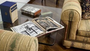 Una stanza con un tavolino da caffè in vetro su cui sono esposti un libro e una scatola blu.