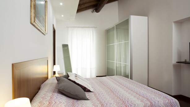 Una camera da letto con un letto, un comodino, una lampada, un armadio e uno specchio.