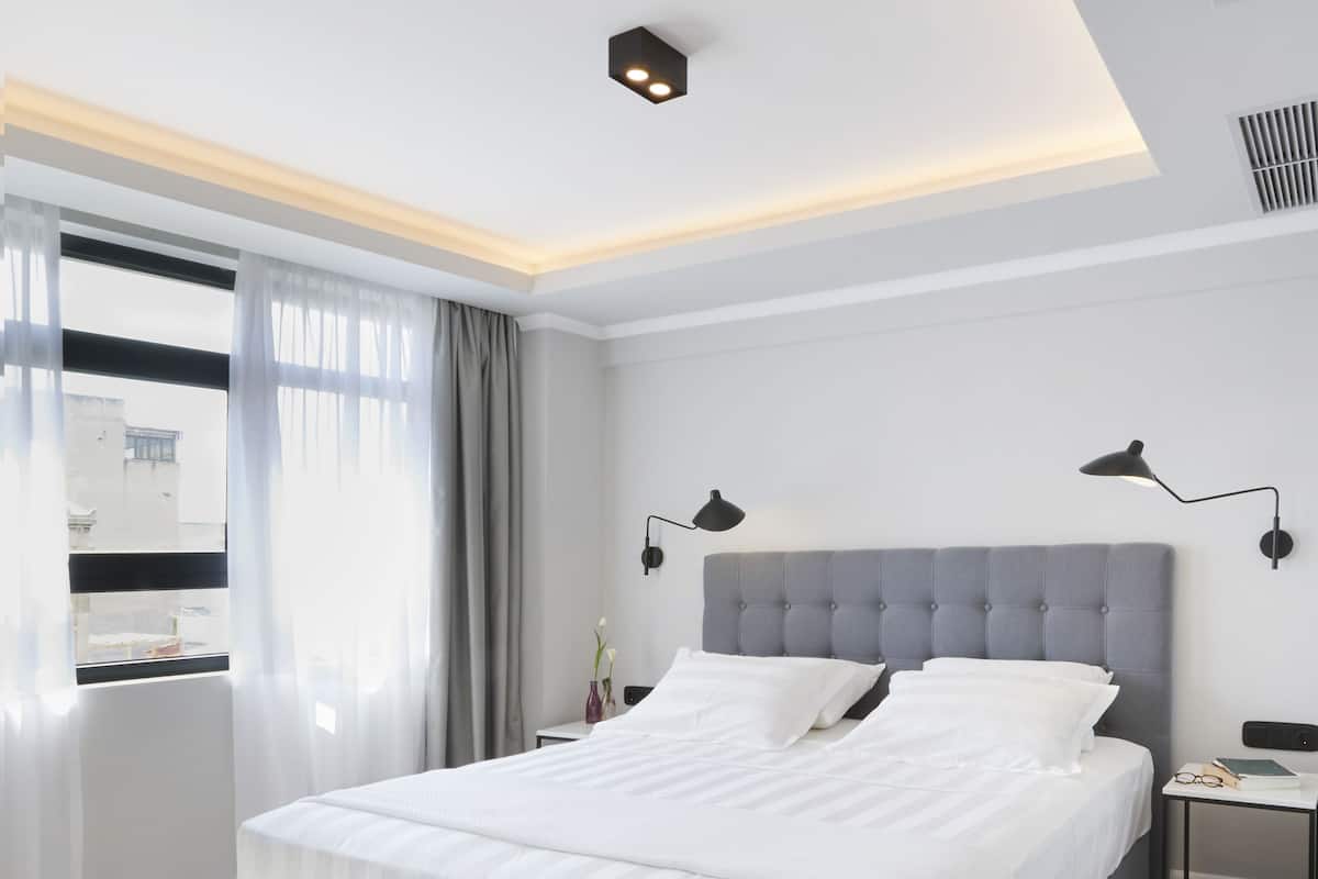 Une chambre moderne avec un grand lit, des tables de chevet et une vue sur la ville.
