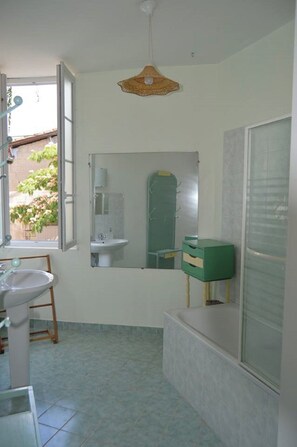 A bathroom with a sink, mirror, and green cabinet.