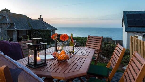 A wooden table with chairs, a lantern, and a fruit bowl. - Godrevy (St Ives)