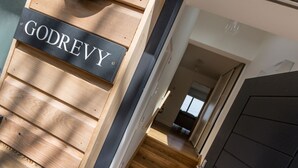 A wooden staircase with a black door and a sign that reads "GODREY". - Godrevy (St Ives)