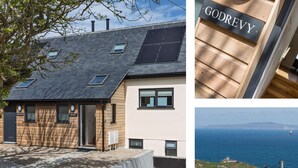 A modern house with a sloped roof, solar panels, and a view of the sea. - Godrevy (St Ives)