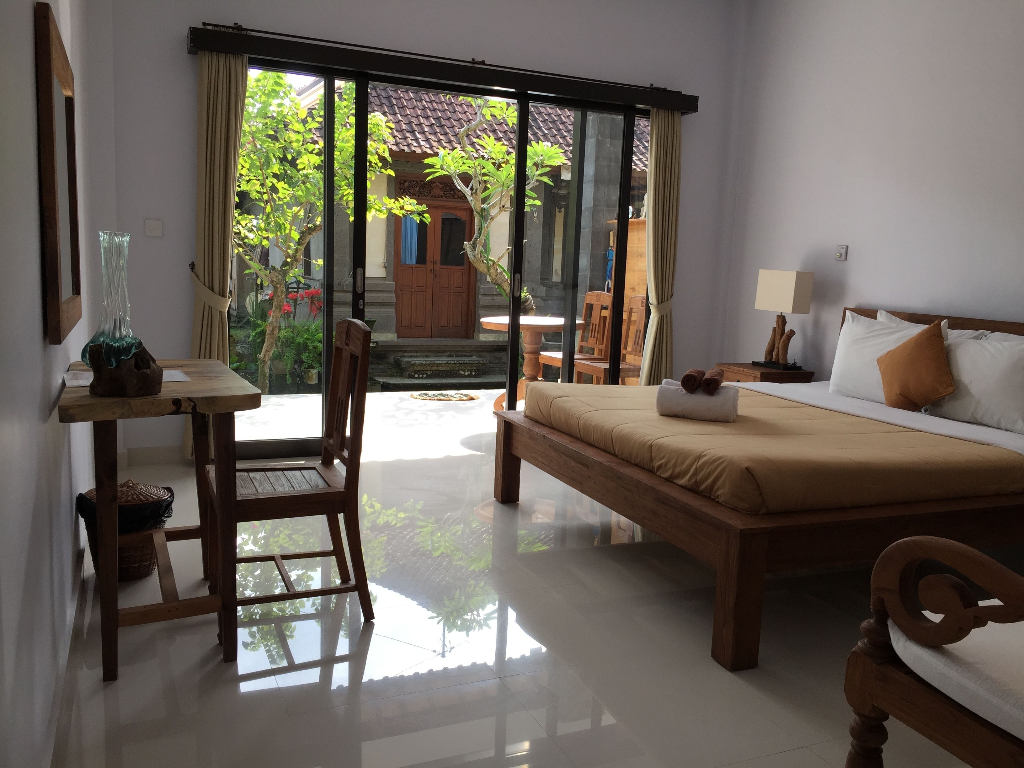A hotel room with a bed, a desk, a chair, and a view of the outside.