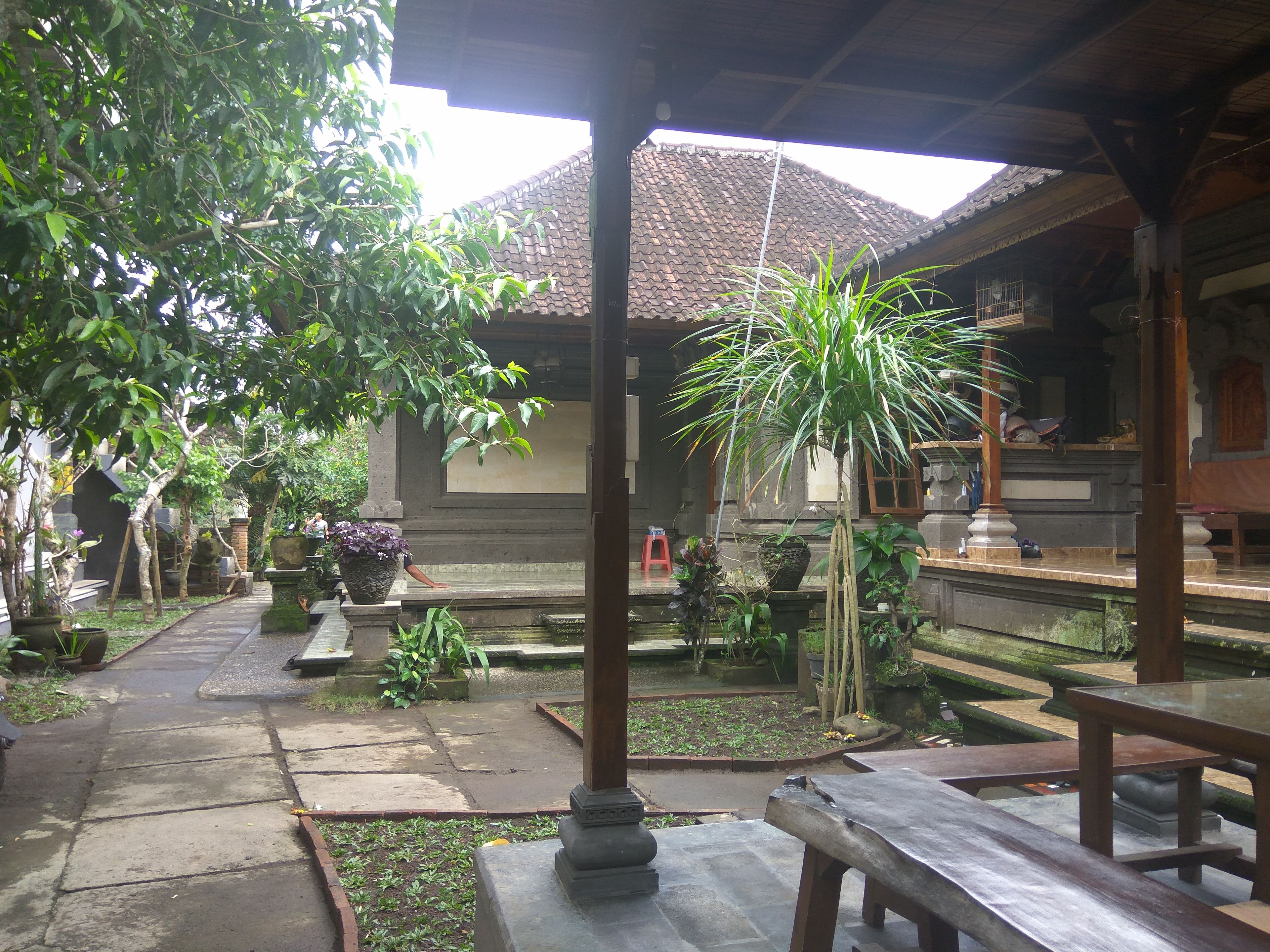 A courtyard with stone benches, potted plants, and a traditional tiled roof structure.