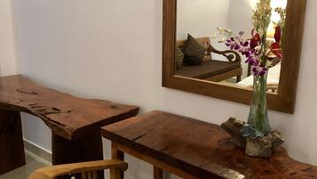 Una mesa de madera con un espejo encima, una silla y un jarrón con flores.