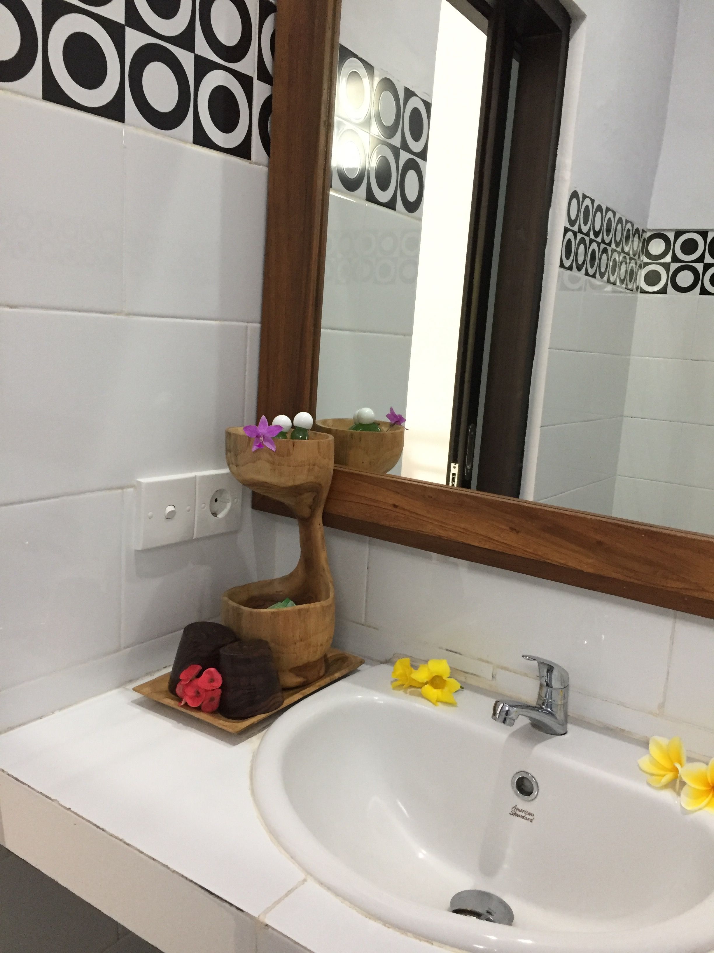 A bathroom with a white sink, a wooden vanity, and a mirror.