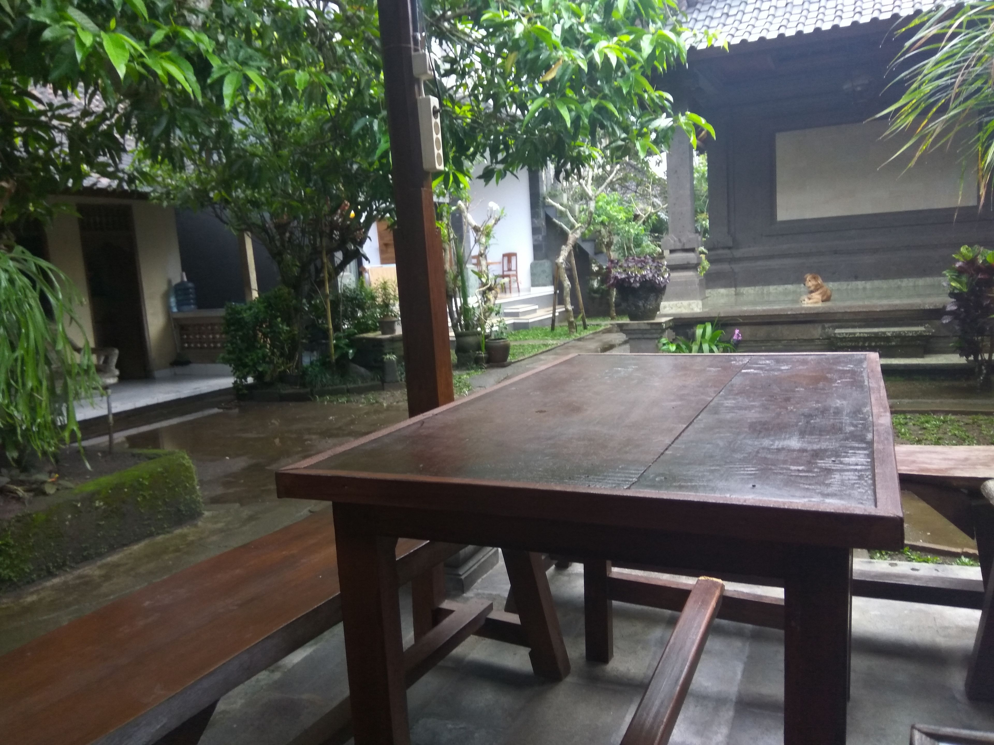 A wooden table in a courtyard with a tiled roof and potted plants.