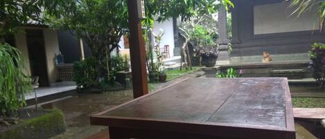 A wooden table in a courtyard with a tiled roof and potted plants.