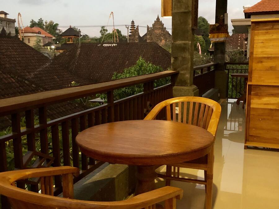 Un tavolo e sedie di legno su un balcone con vista su edifici tradizionali e un tempio sullo sfondo.