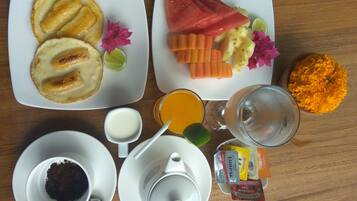 Une table mise pour le petit-déjeuner, avec des assiettes de nourriture, un verre de jus d’orange, une tasse de café et des condiments.
