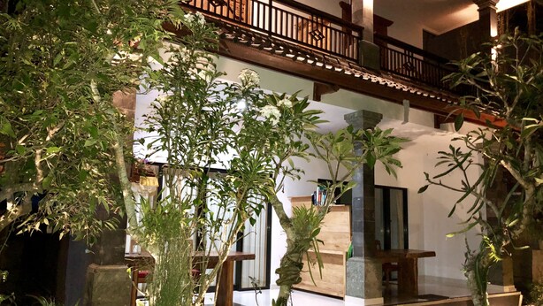 A traditional building with a wooden balcony, indoor plants, and a staircase leading to an upper level. - The Hidden Bali Inn (Ubud)
