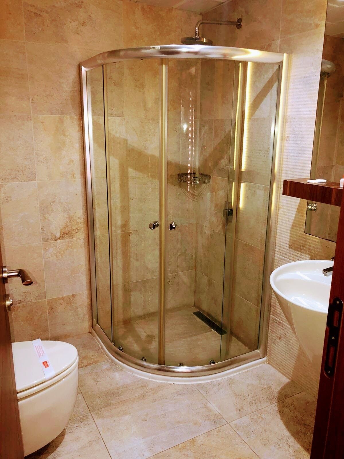 A modern bathroom with a glass-enclosed shower, a toilet, and a sink.