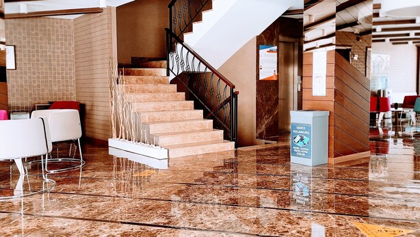 A spacious lobby with a marble floor, a staircase with a metal railing, and a modern ceiling design. - Feyzan Hotel (Corum)