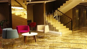 A lobby with a marble floor, a staircase, and seating areas with chairs and a table. - Feyzan Hotel (Corum)