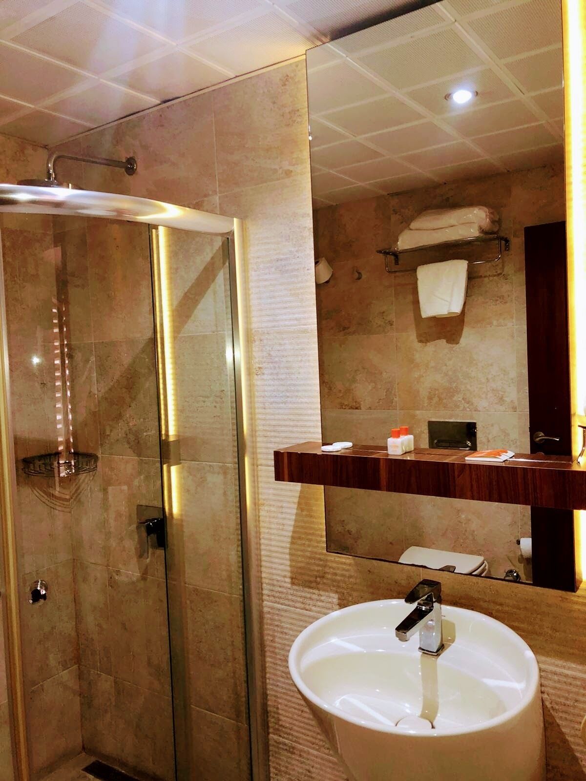 Un bagno moderno con cabina doccia in vetro, uno specchio grande e un mobile lavabo.