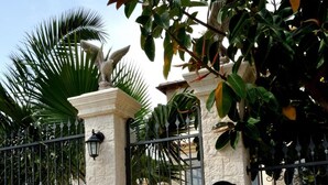 A gated entrance with a stone wall, a metal gate, and a statue. - B&B Nicole (Palma di Montechiaro)