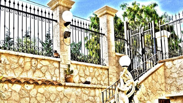 A stone staircase with potted plants, a metal fence, and a statue. - B&B Nicole (Palma di Montechiaro)