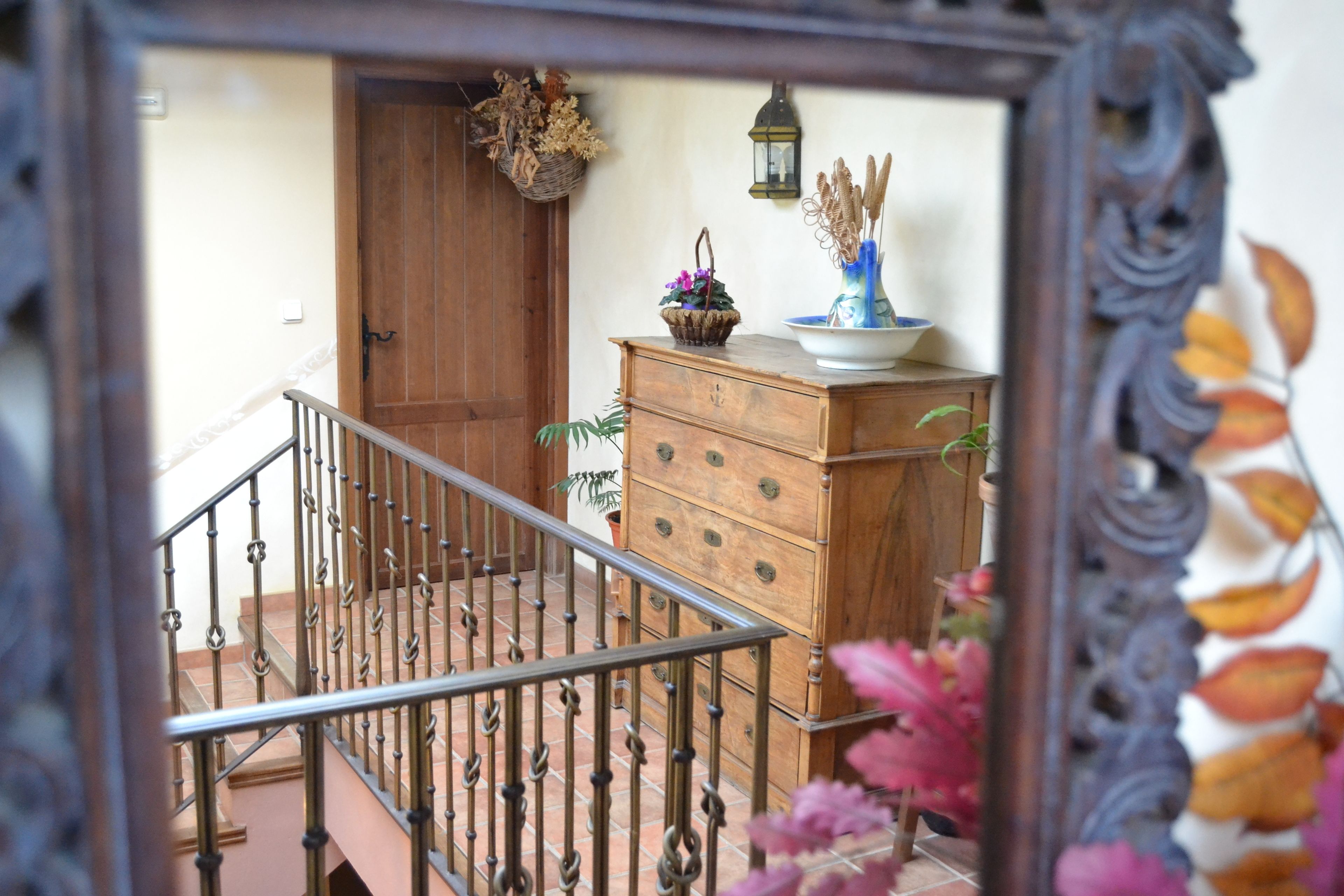 A wooden staircase with a metal railing, a wooden door, and a dresser with drawers and decorative items.