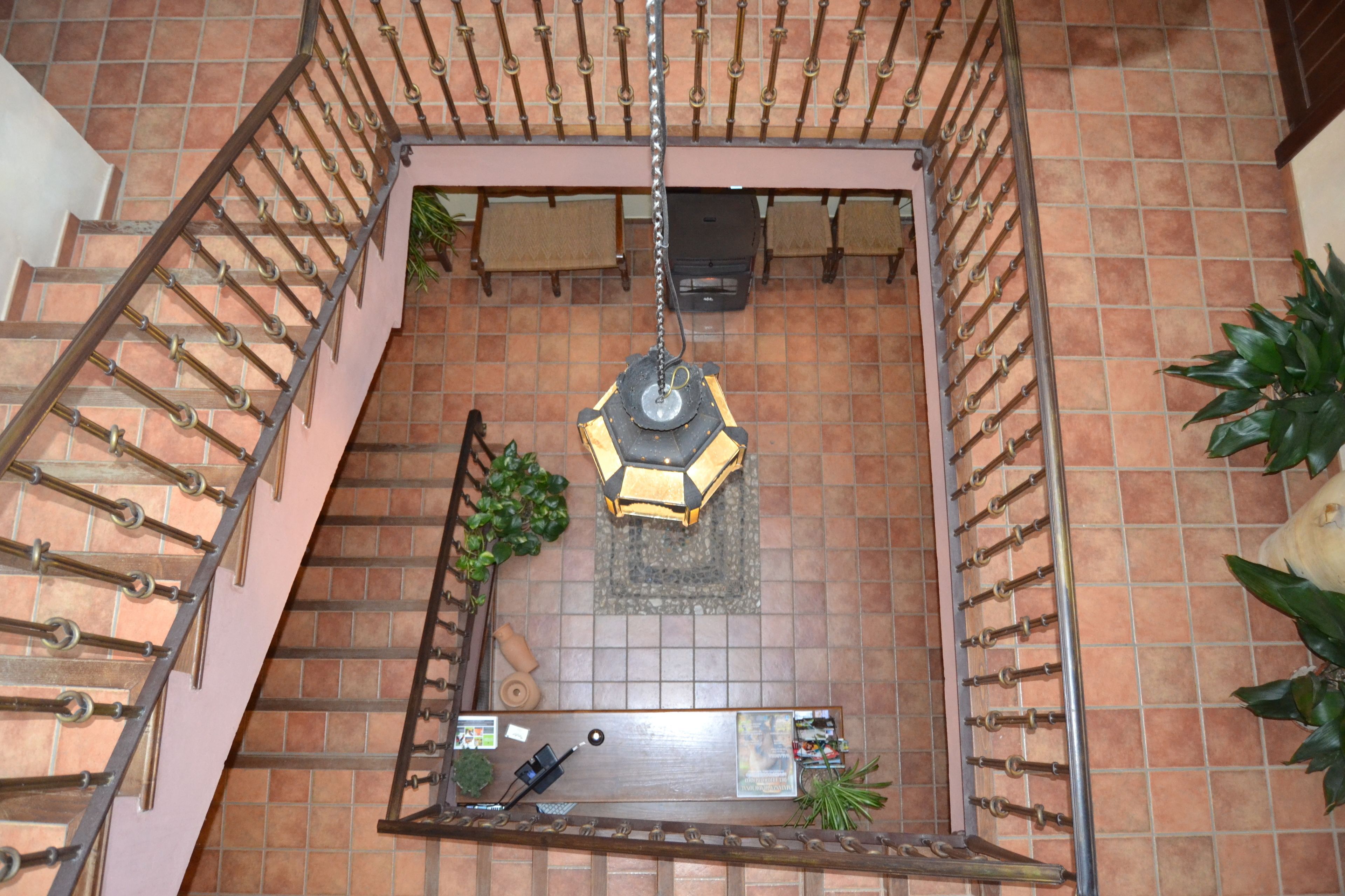 Un vaste atrium doté d’un lustre central, d’un sol carrelé et d’un escalier avec des rampes en métal.