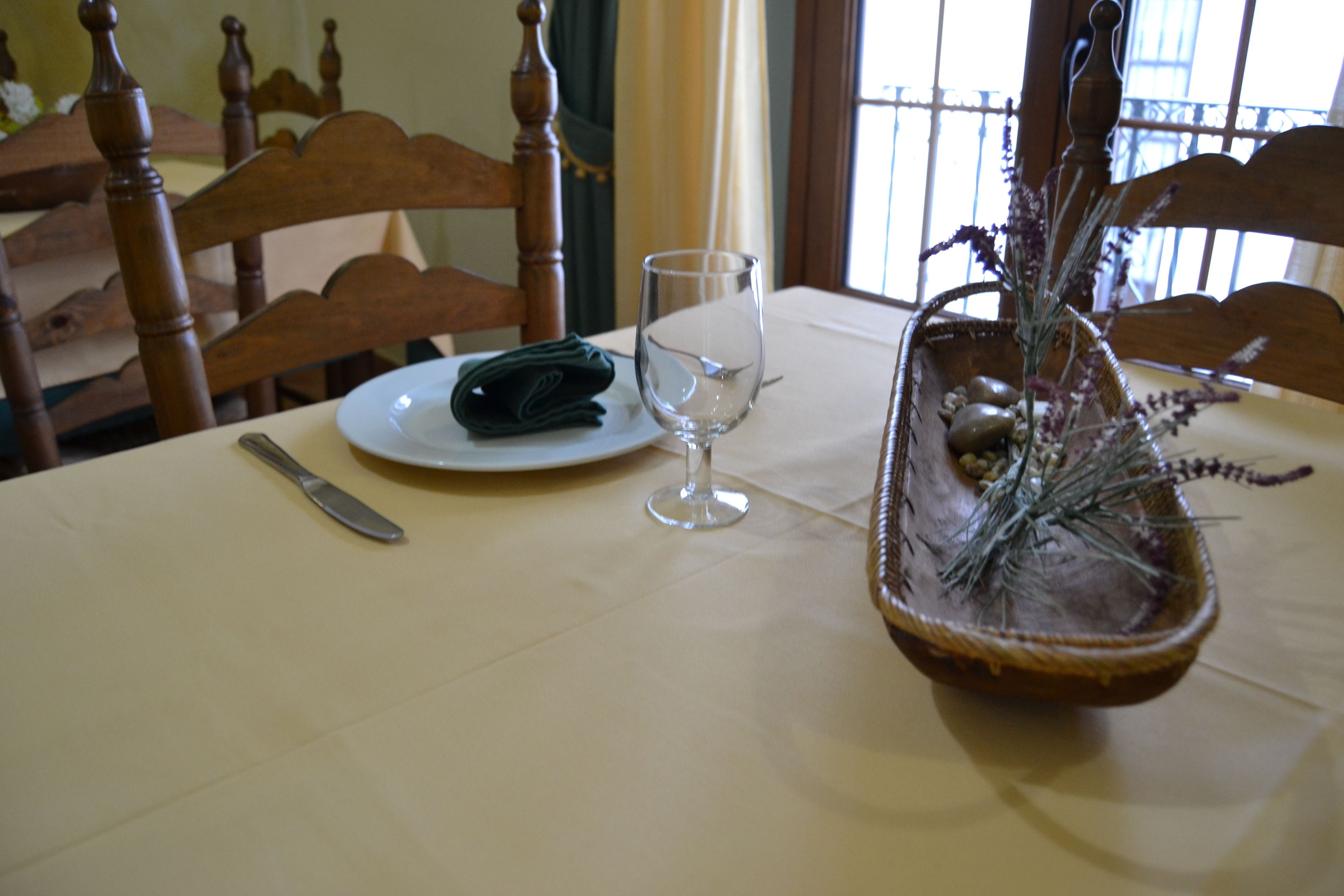 A dining table with a folded napkin, a wine glass, and a decorative basket with dried plants.