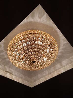 Un lustre orné de nombreux cristaux transparents, le tout monté sur une structure dorée.