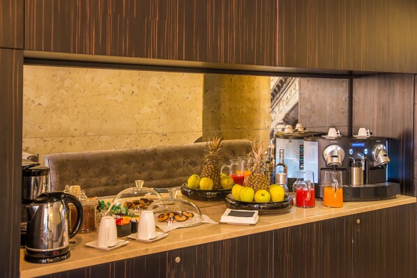 Balcão de café da manhã com máquina de café, frutas e uma balança.