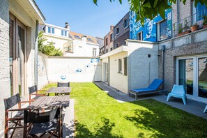 Un patio con zona de comedor, una silla de lounge y una pequeña mesa.