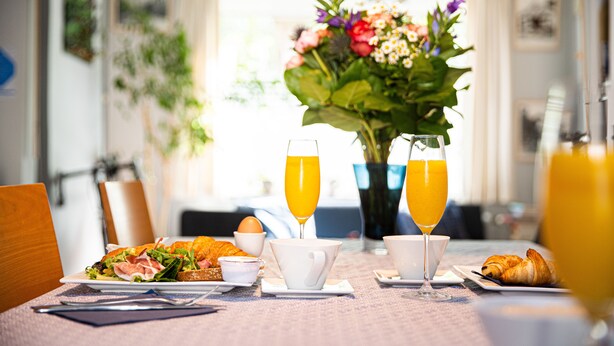 A breakfast setting with croissants, a sandwich, and orange juice on a table.