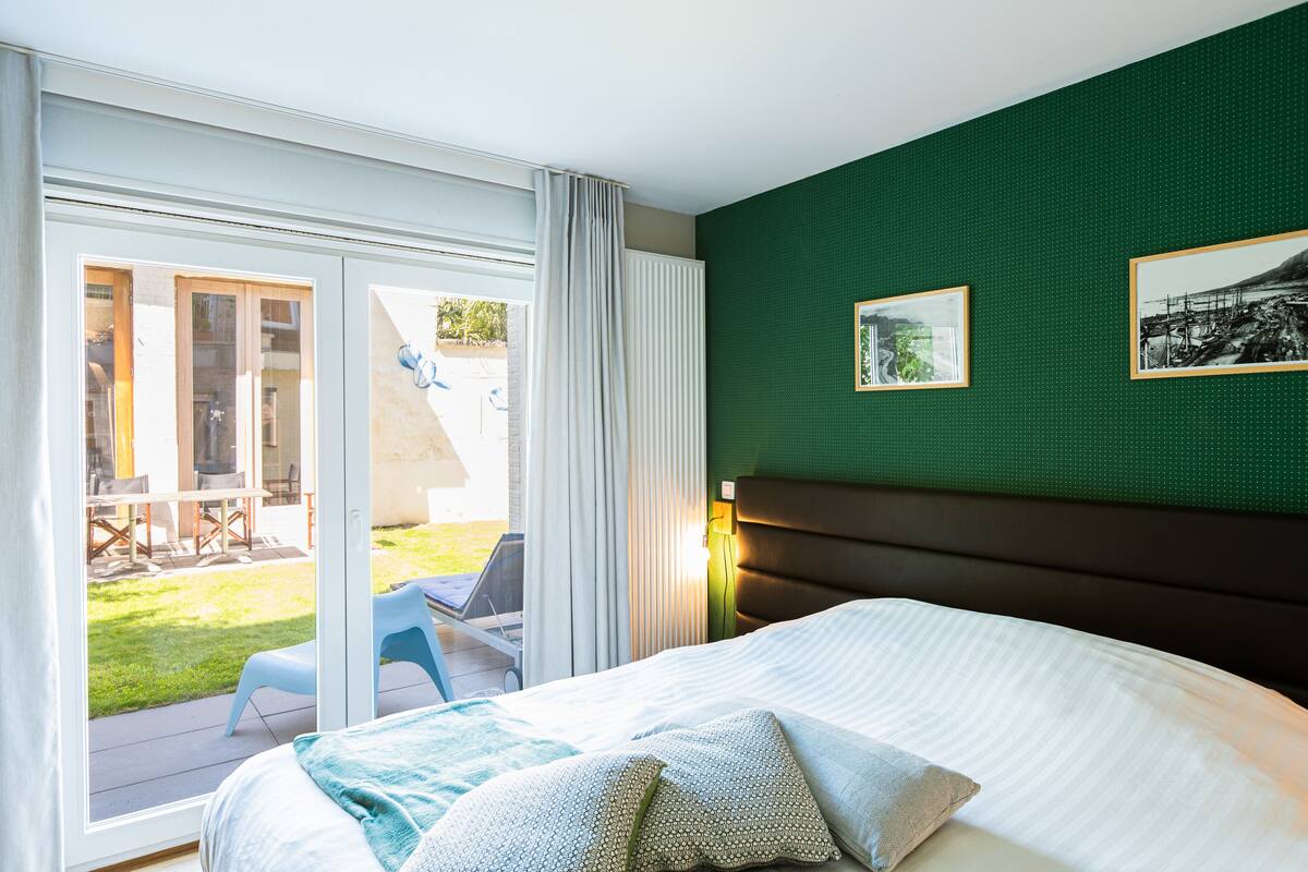 A hotel room with a bed, a view of the outdoor patio, and two framed pictures on the wall.