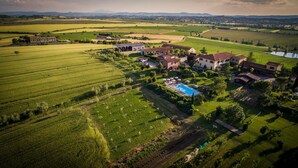 Luchtbeeld van een woonwijk met huizen, een zwembad en omliggende landbouwvelden.