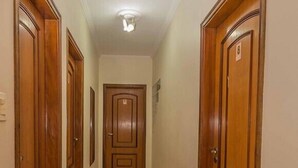 A hallway with wooden doors, a tiled floor, and a ceiling light. - Pousada F7 (Campinas)