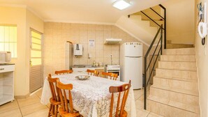 A compact kitchen with a dining table, chairs, a refrigerator, and a stove. - Pousada F7 (Campinas)