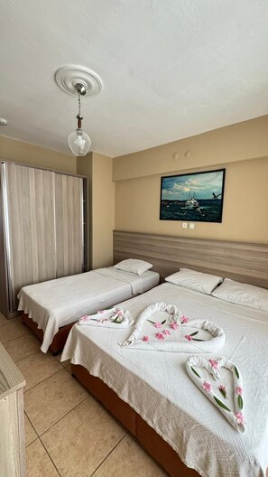 Habitación de hotel con dos camas, un cuadro de un barco en la pared y una lámpara en el techo.