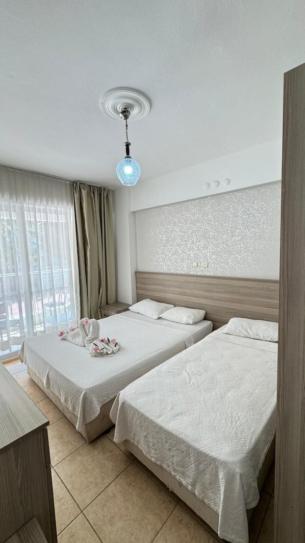 A hotel room with two beds, a wooden headboard, a ceiling light, and a view through the window.