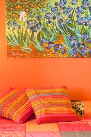 A bed with colorful pillows and a painting of flowers on the wall. - Pazo de Verdes (Cospeito)