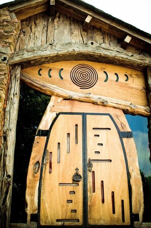 Una puerta de madera rústica con un diseño circular encima, ubicada en un muro de piedra.