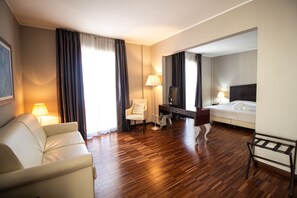 A hotel room with a wooden floor, a bed, a desk, a chair, and a sofa. - LVG Hotel Collection - Cavour (Novara)