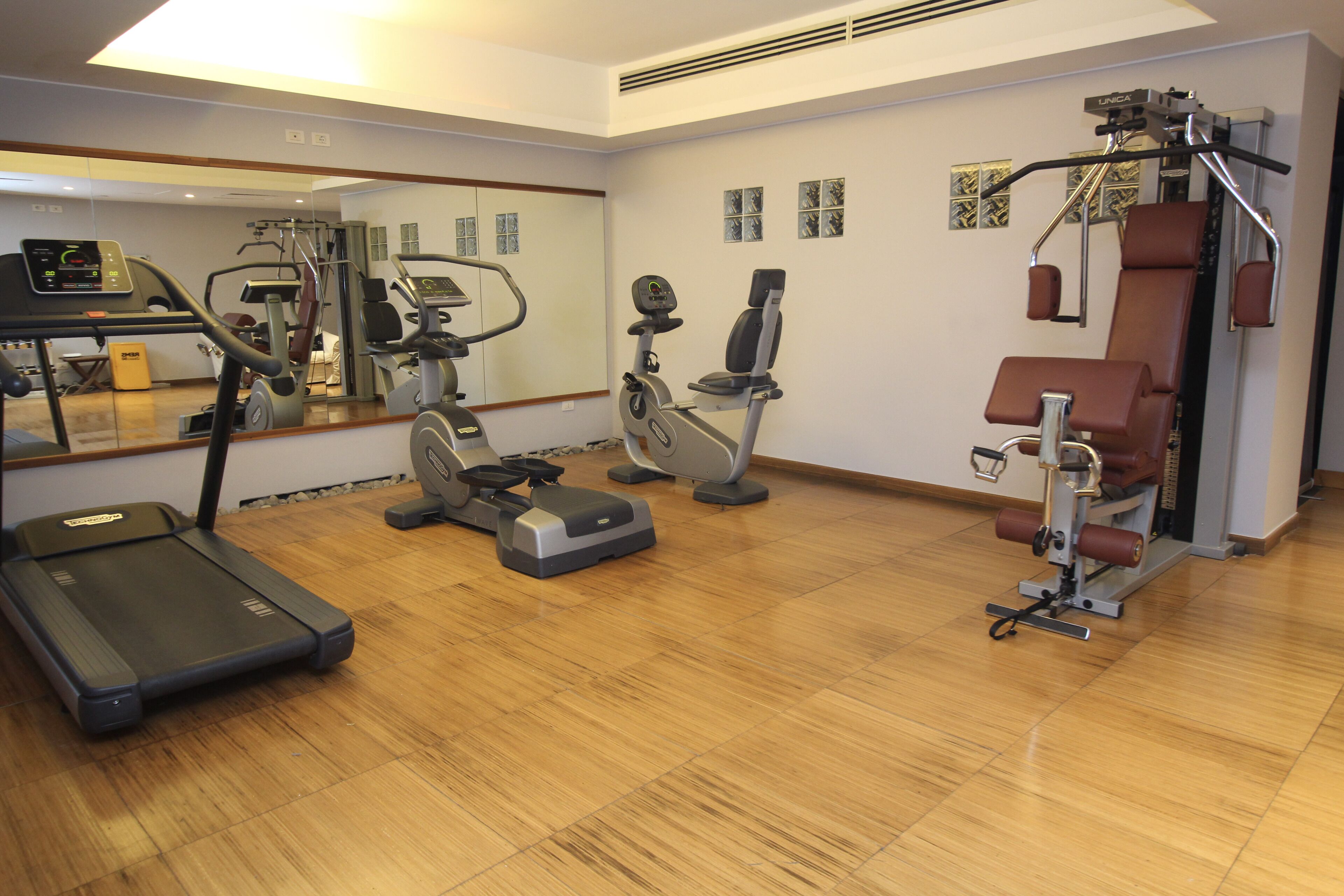 Un gimnasio con cinta de correr, elíptica, bicicleta estática y escaladora.