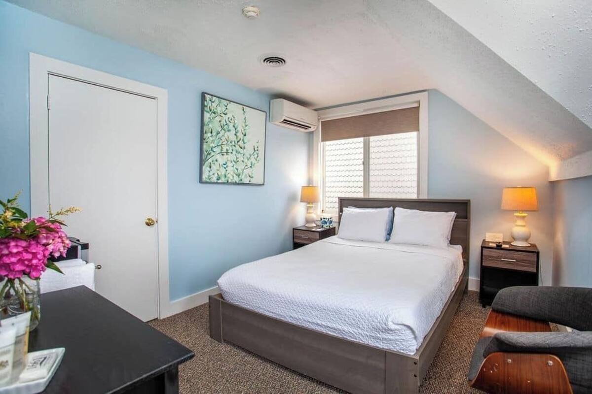 A hotel room with a bed, bedside tables, a desk, and a chair.