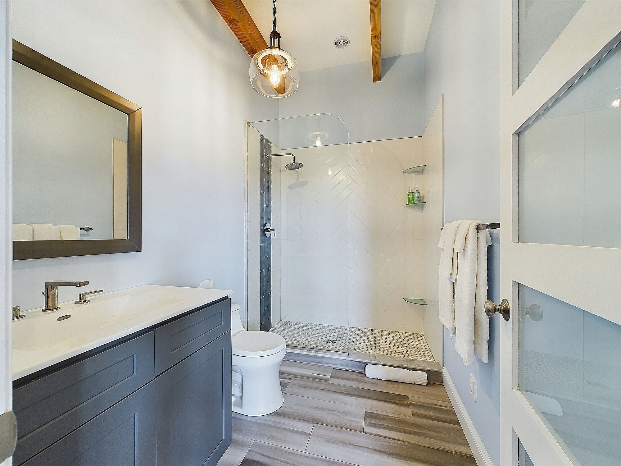 A modern bathroom with a shower, toilet, and vanity.