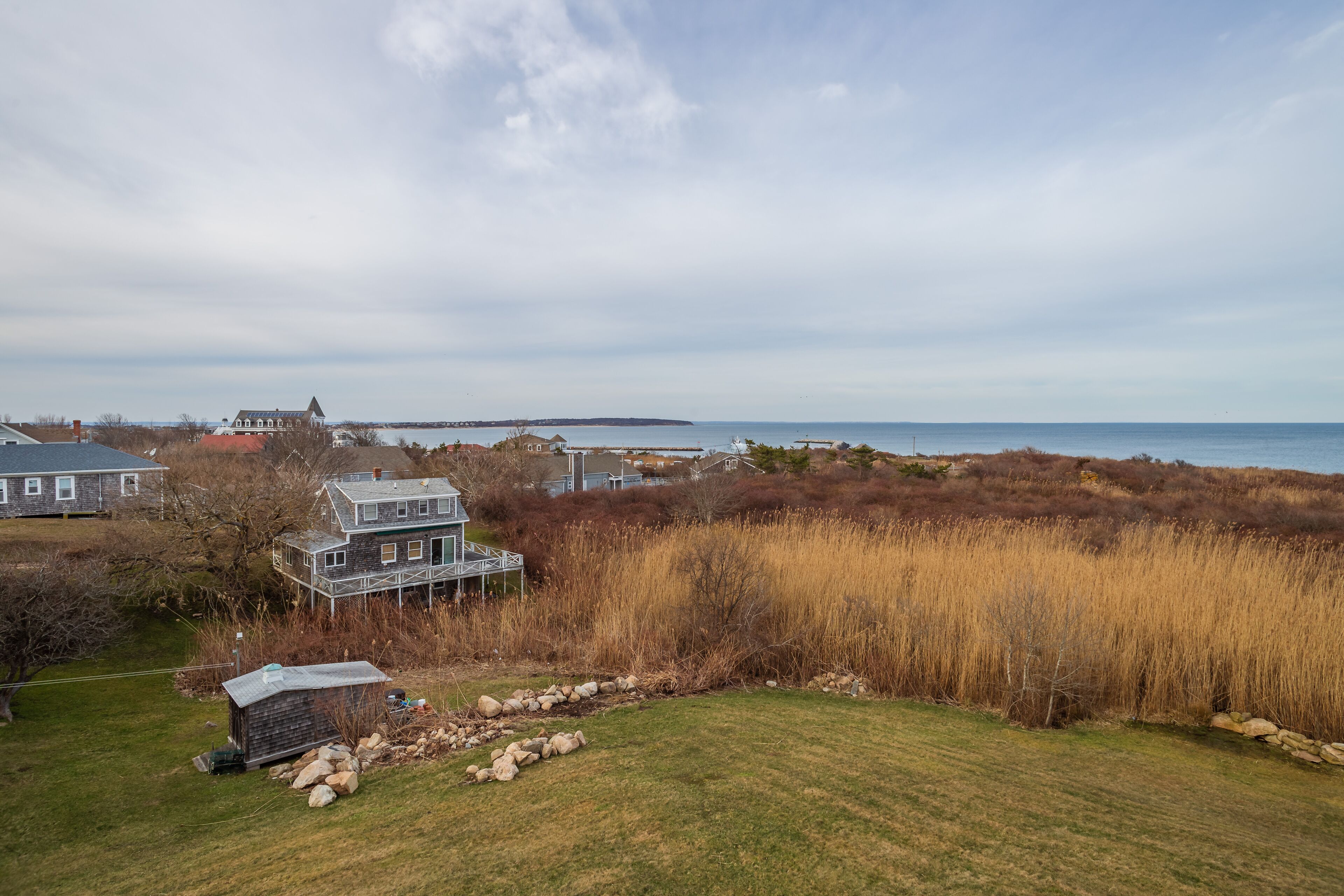 A coastal property with a large house, a smaller cabin, and a view of the sea.