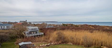 A coastal property with a large house, a smaller cabin, and a view of the sea.