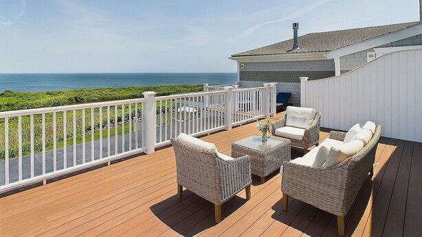 A deck with wicker furniture and a white railing overlooking the ocean. - The 1661 Inn (Block Island)