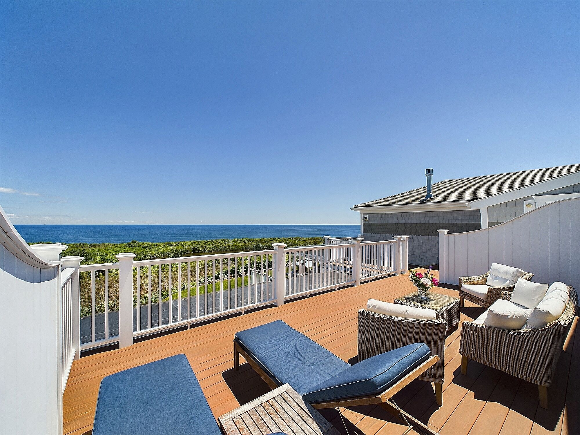 A deck with lounge chairs and a view of the ocean.