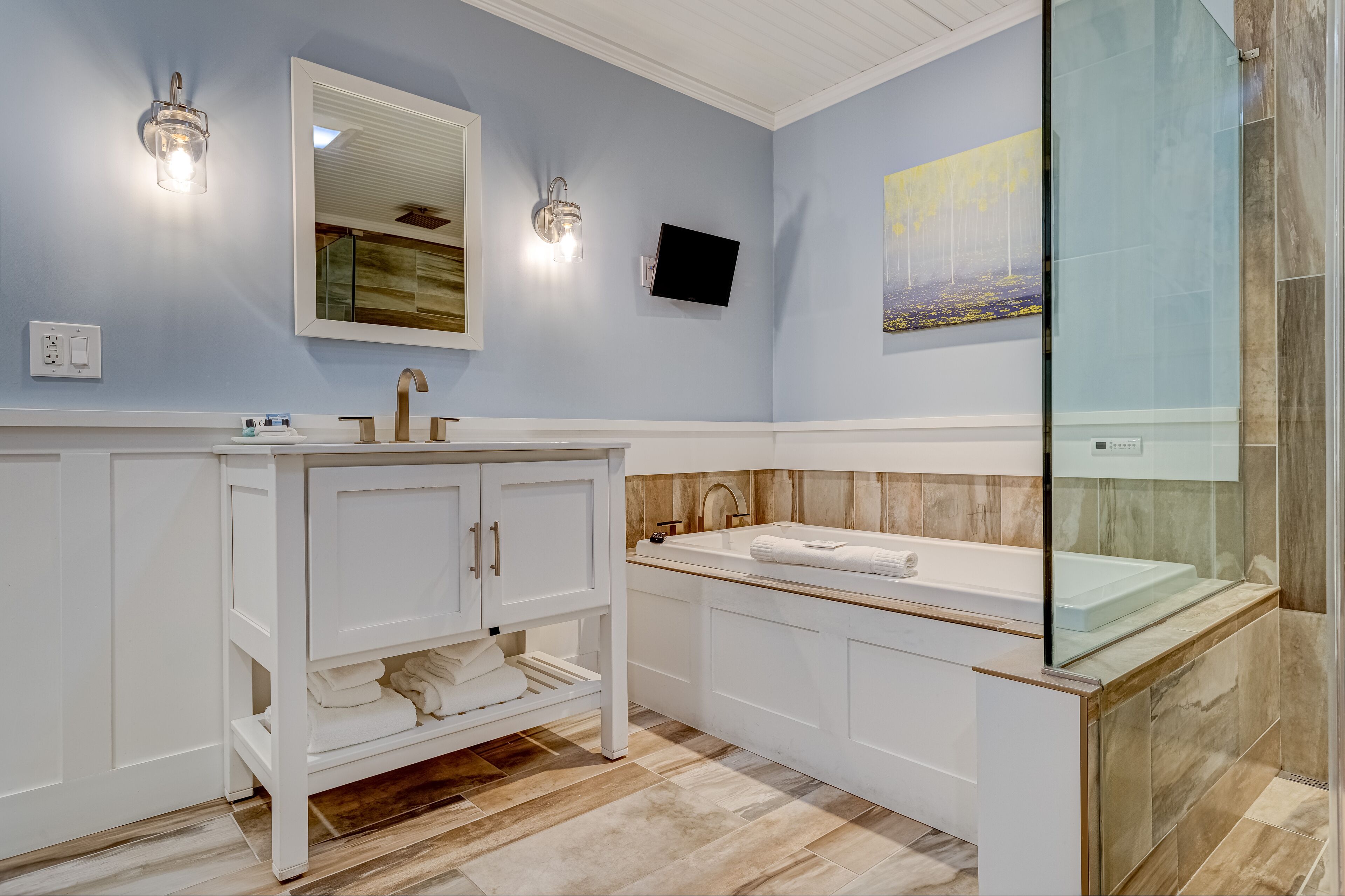 A modern bathroom with a white vanity, a bathtub, and a glass shower enclosure.